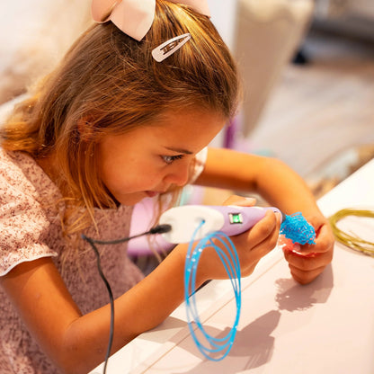 Barn laver kreativt kunstprojekt med 3D pen og blå plastfilament ved bord