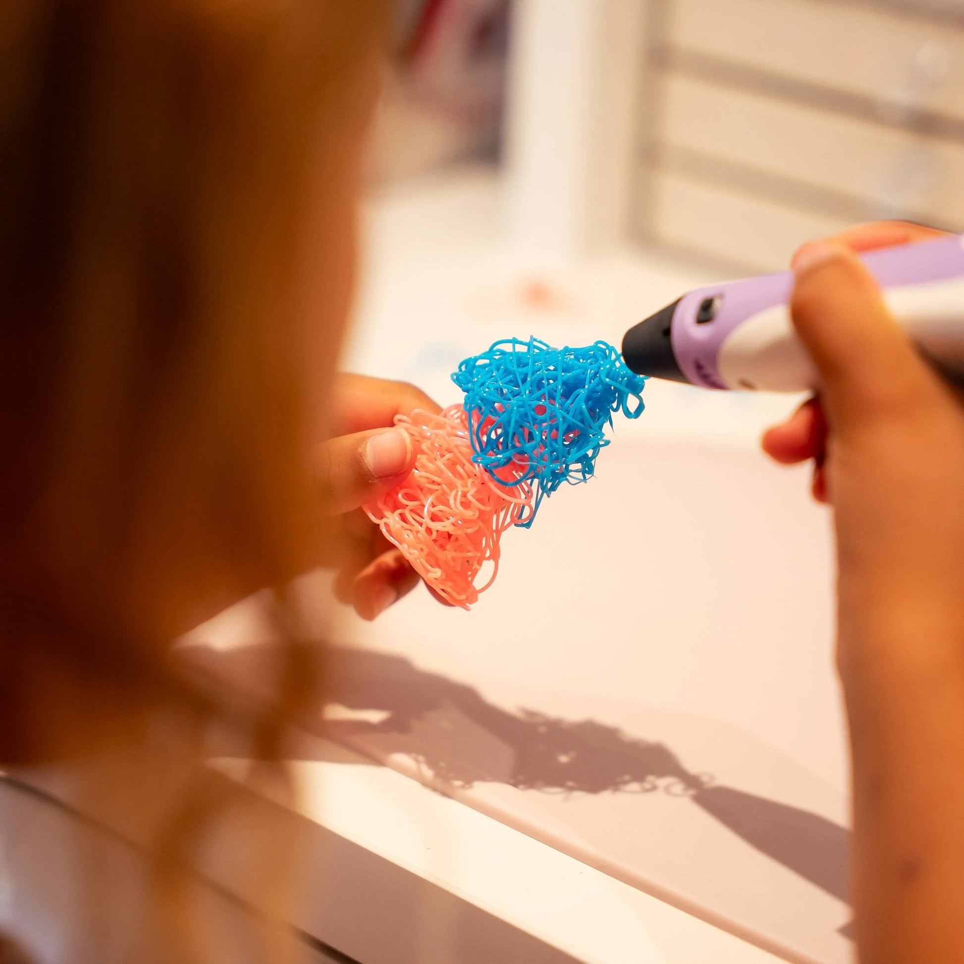 Barn bruger 3D pen til at lave farverig figur i blå og lyserød plastik